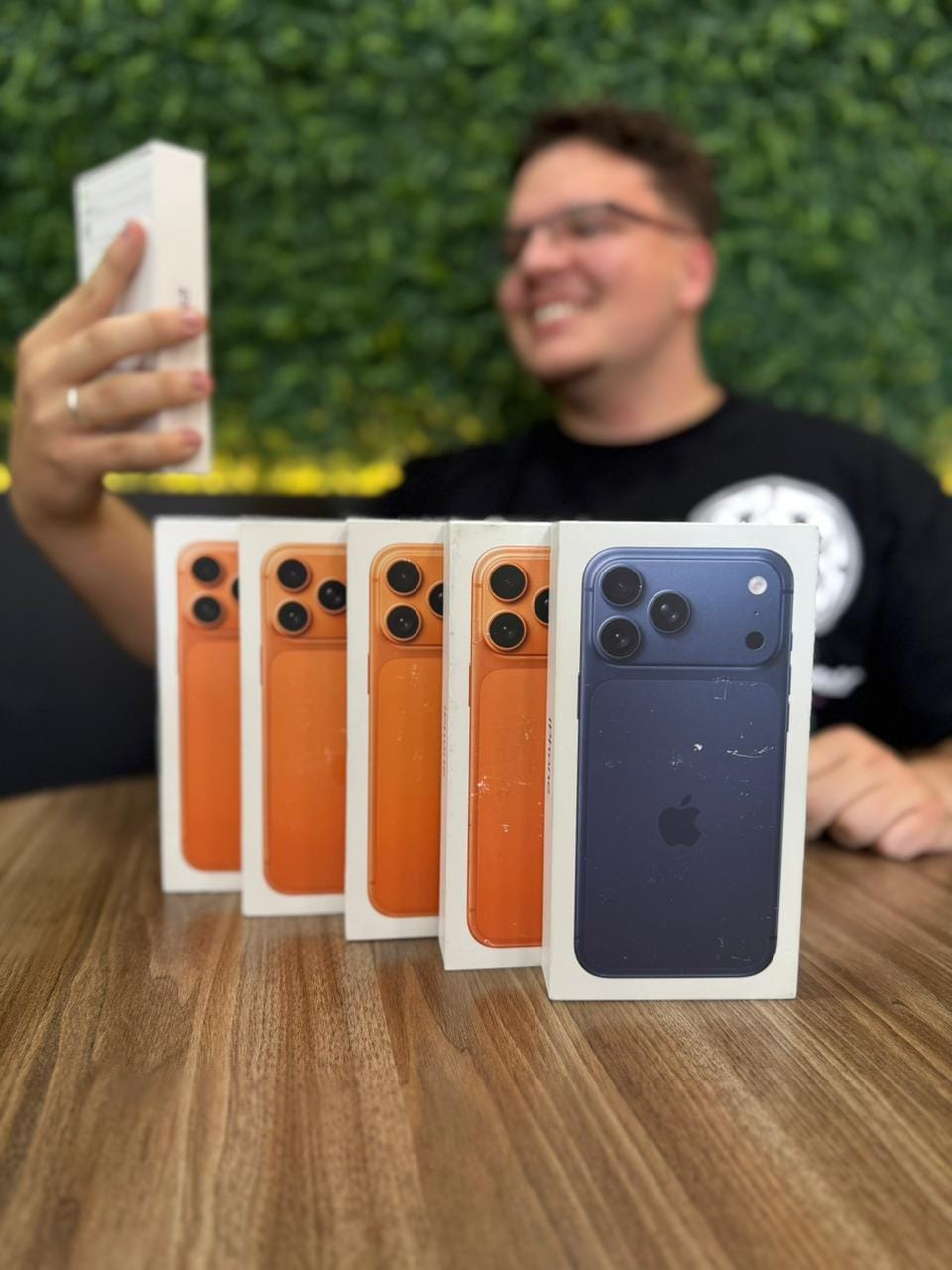 Atendente da South Import's mostrando iPhone 17 Pro lacrados sobre a mesa
